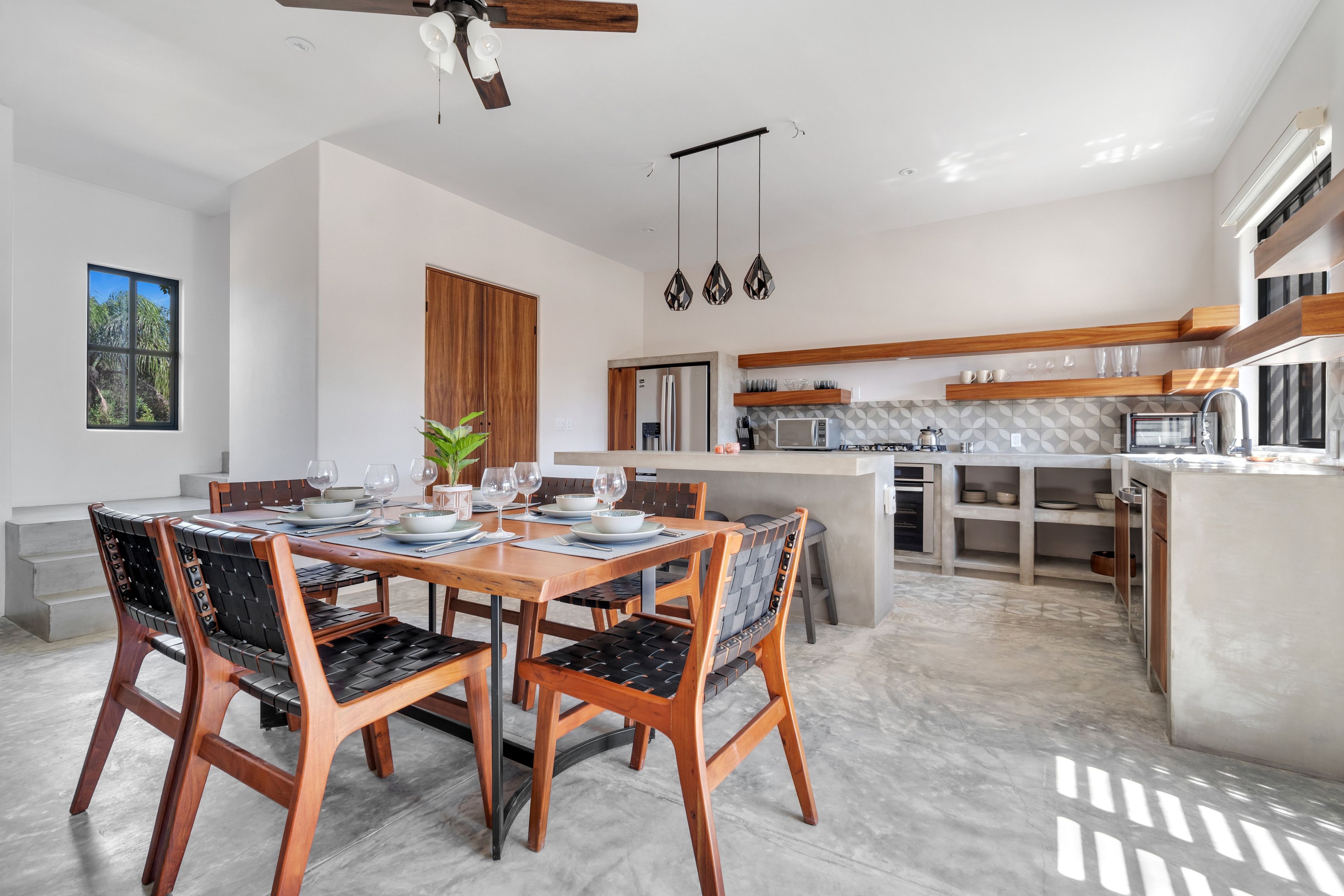 Una cocina moderna con una isla central, armarios de madera y un comedor con mesa y sillas.
