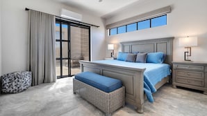 Un dormitorio con una cama grande, una mesita de noche, un banco, una ventana y un equipo de aire acondicionado.