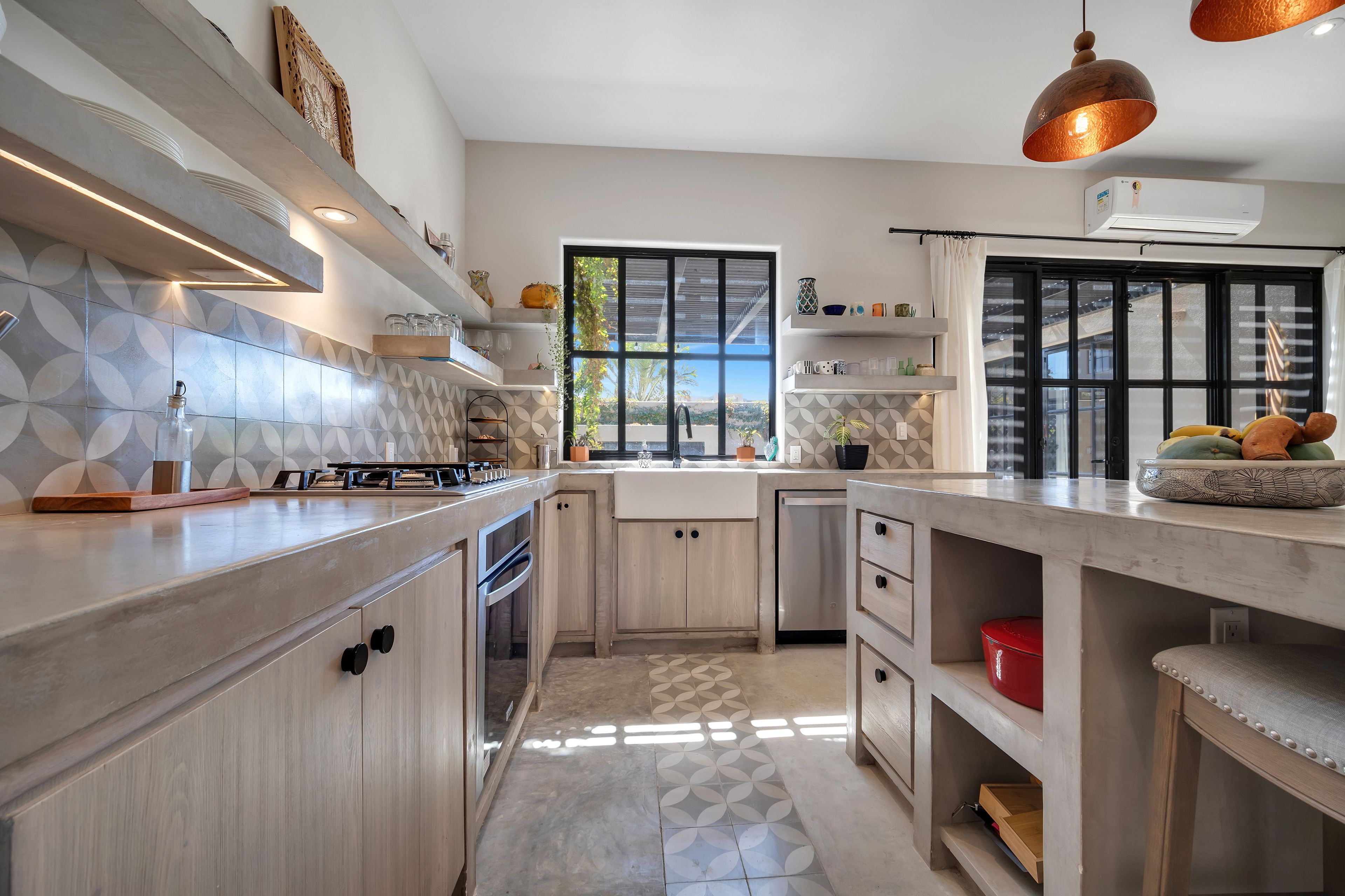 A modern kitchen with a central island, built-in appliances, and a view through the window.