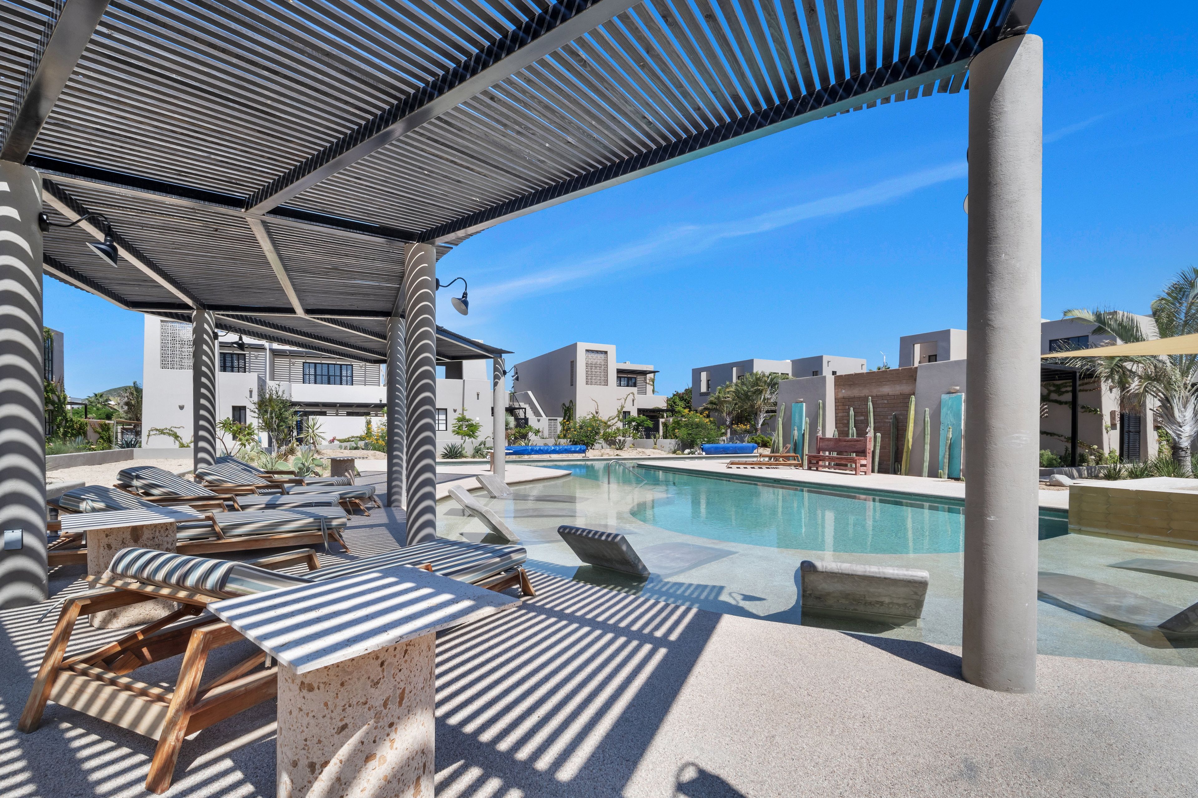 A poolside area with lounge chairs and a covered seating area.