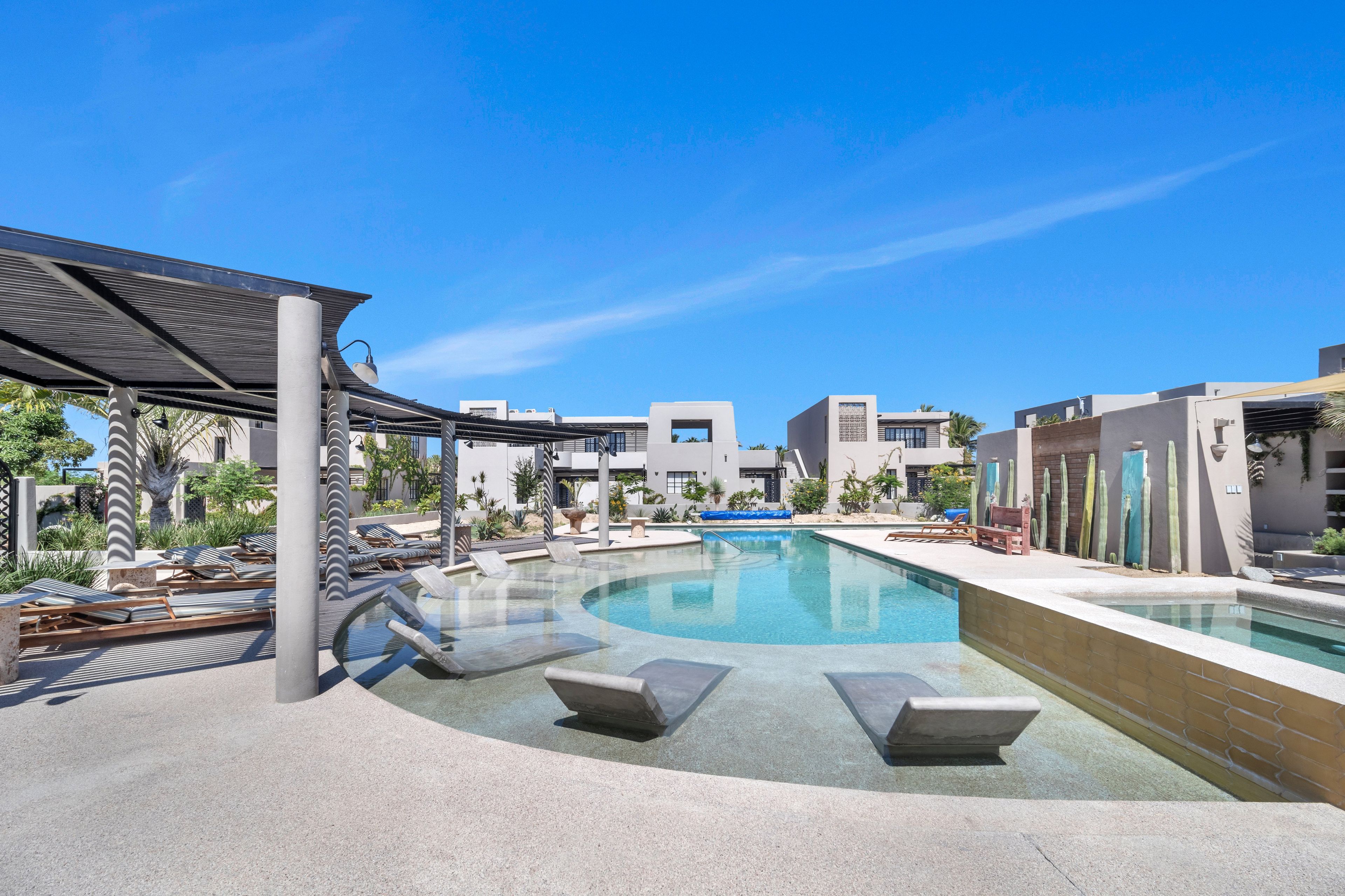 A pool area with lounge chairs and a covered seating area.