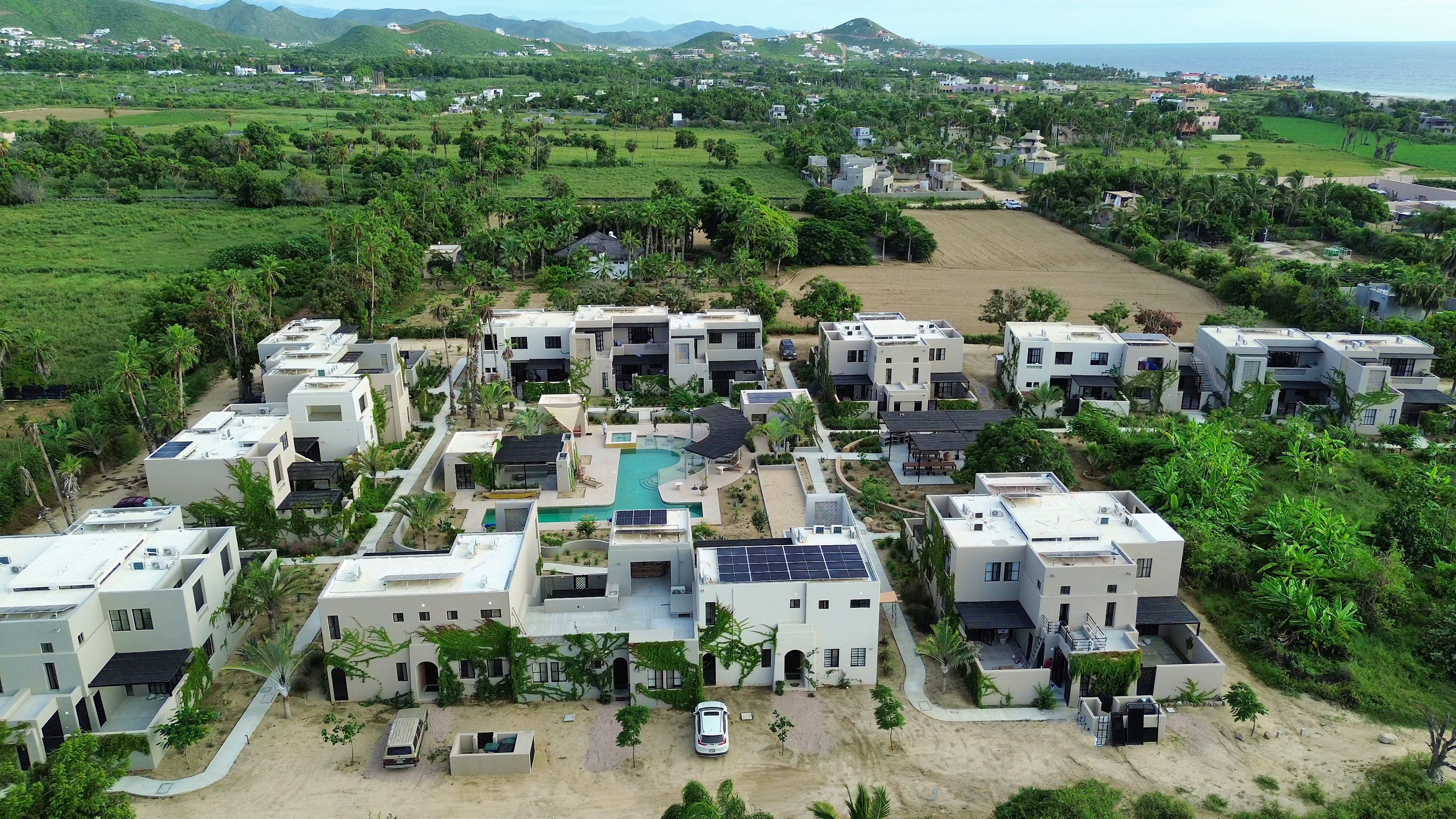 Un barrio residencial con edificios modernos, una piscina y vista al mar.