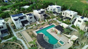 Un complejo residencial con varias casas modernas, una piscina y paneles solares en los tejados.