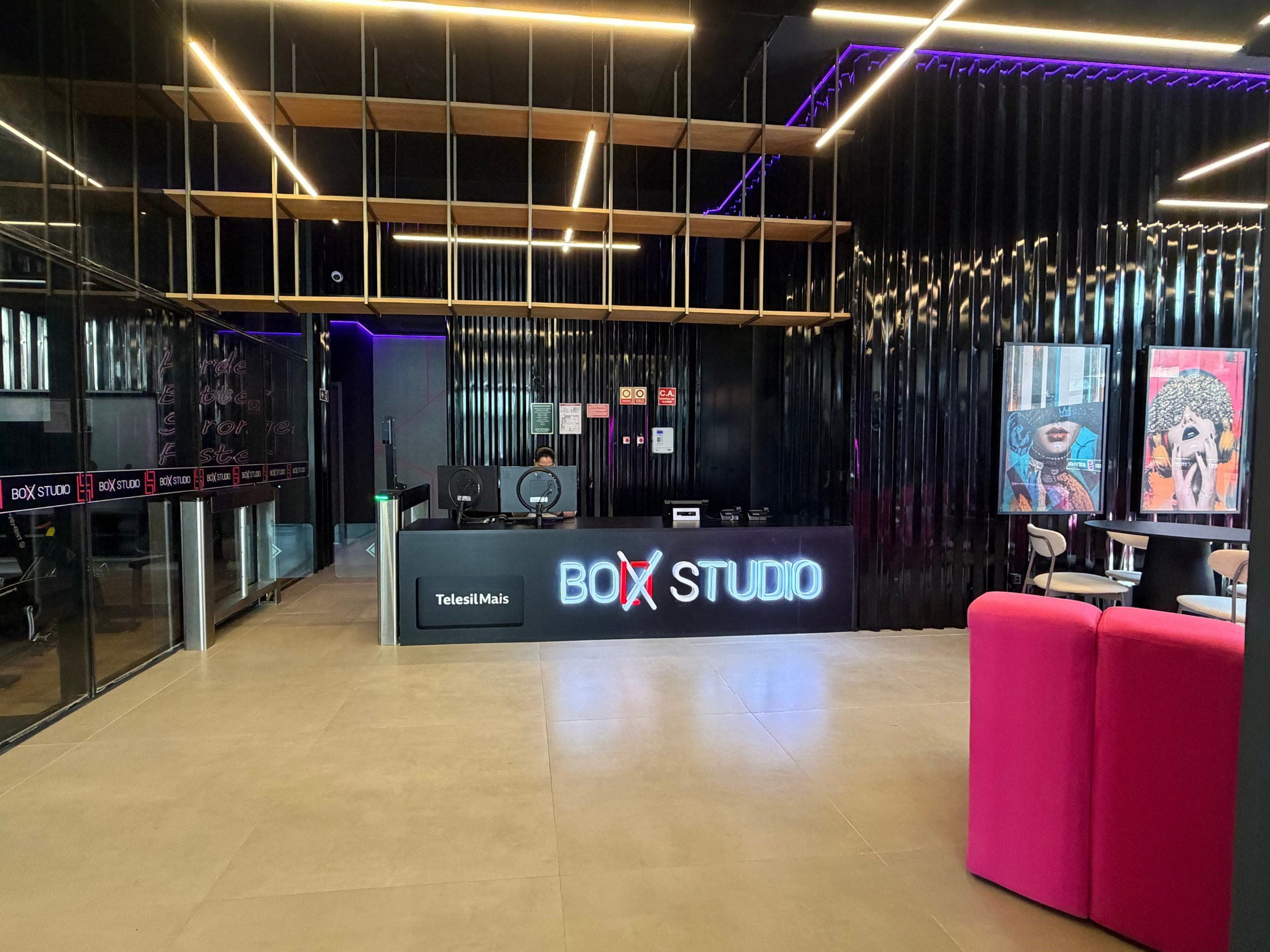A modern interior with a reception desk labeled 'BOX STUDIO,' a glass partition, and a red seating area.