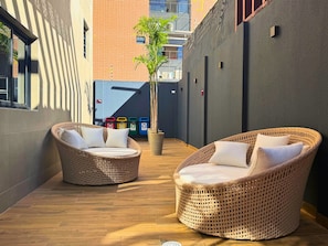 A sunlit outdoor seating area with wicker chairs and a potted plant. - AL - BXSU - Box Studio (Maceió)