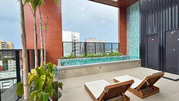 A rooftop terrace with a swimming pool, lounge chairs, and potted plants.
