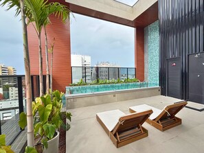 A rooftop terrace with a swimming pool, lounge chairs, and potted plants. - AL - BXSU - Box Studio (Maceió)