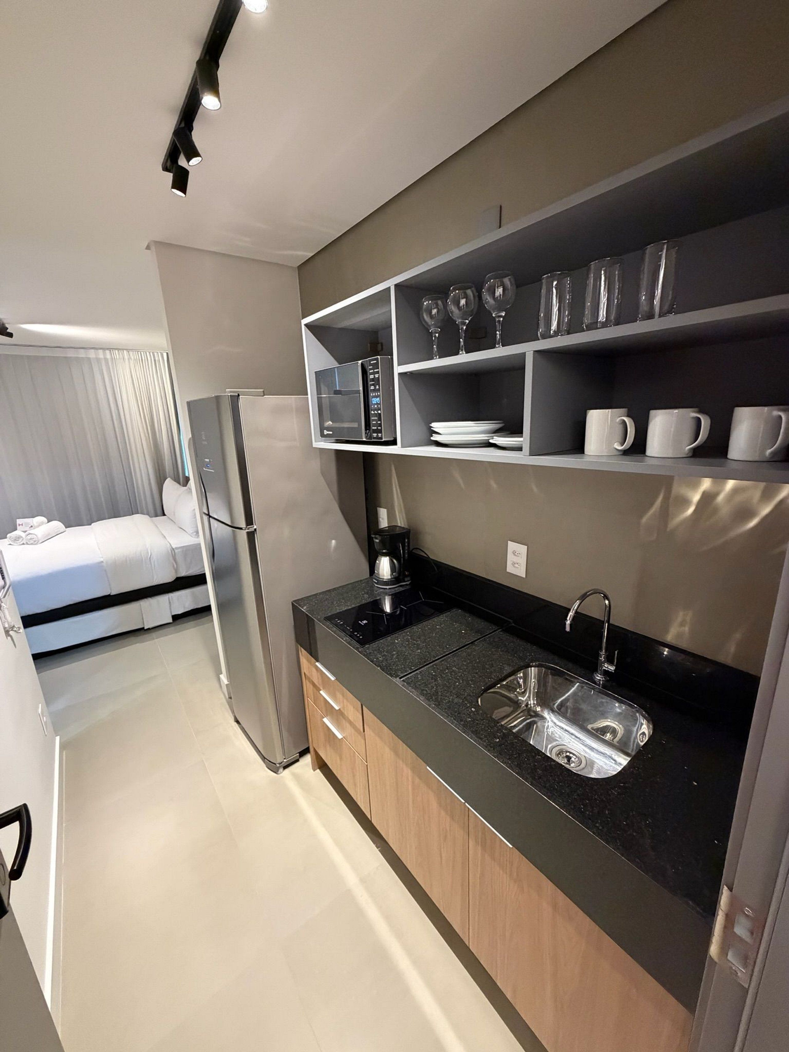 Una cocina compacta con microondas, cafetera y lavamanos.