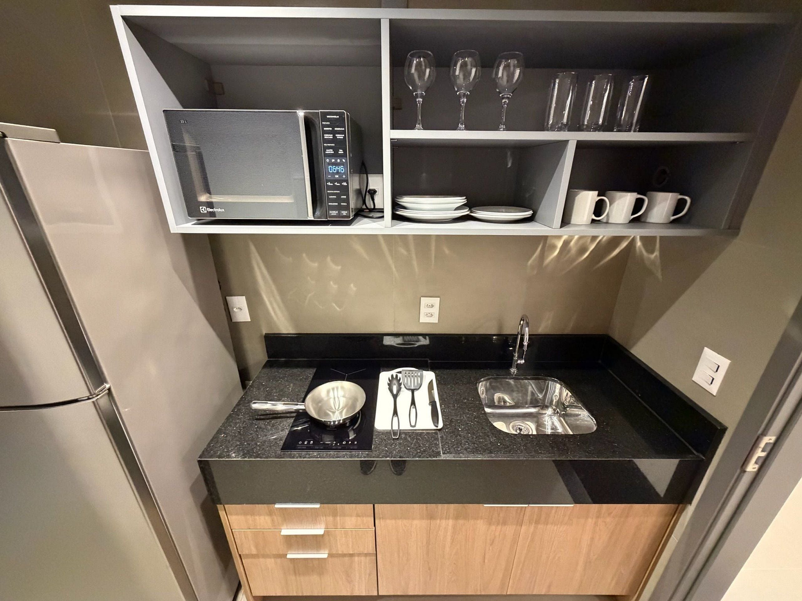 Une cuisine compacte équipée d’un four à micro-ondes, d’une cuisinière, d’un évier et de placards de rangement.