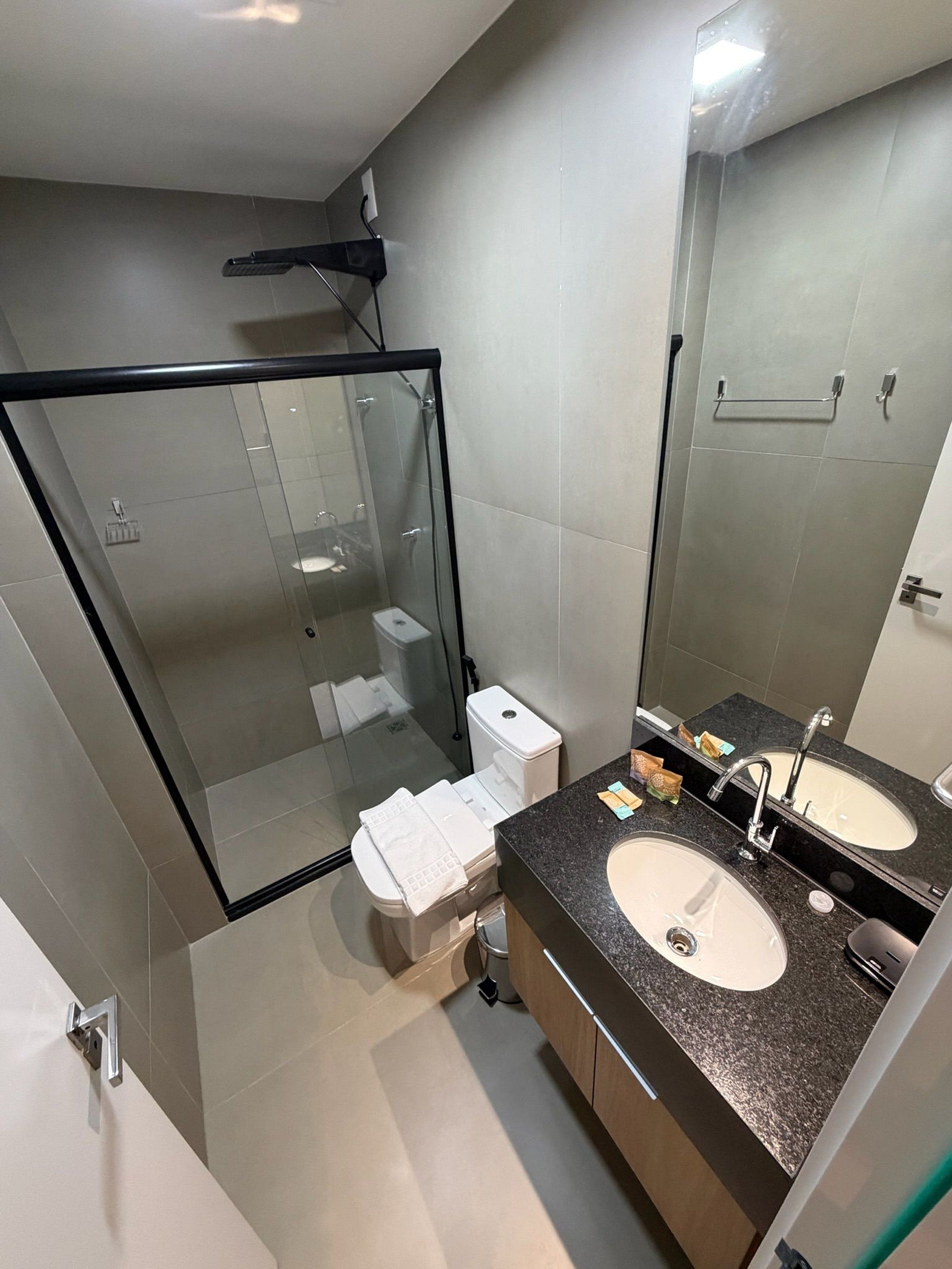 Un baño moderno con ducha envuelta en vidrio, inodoro y tocador doble.