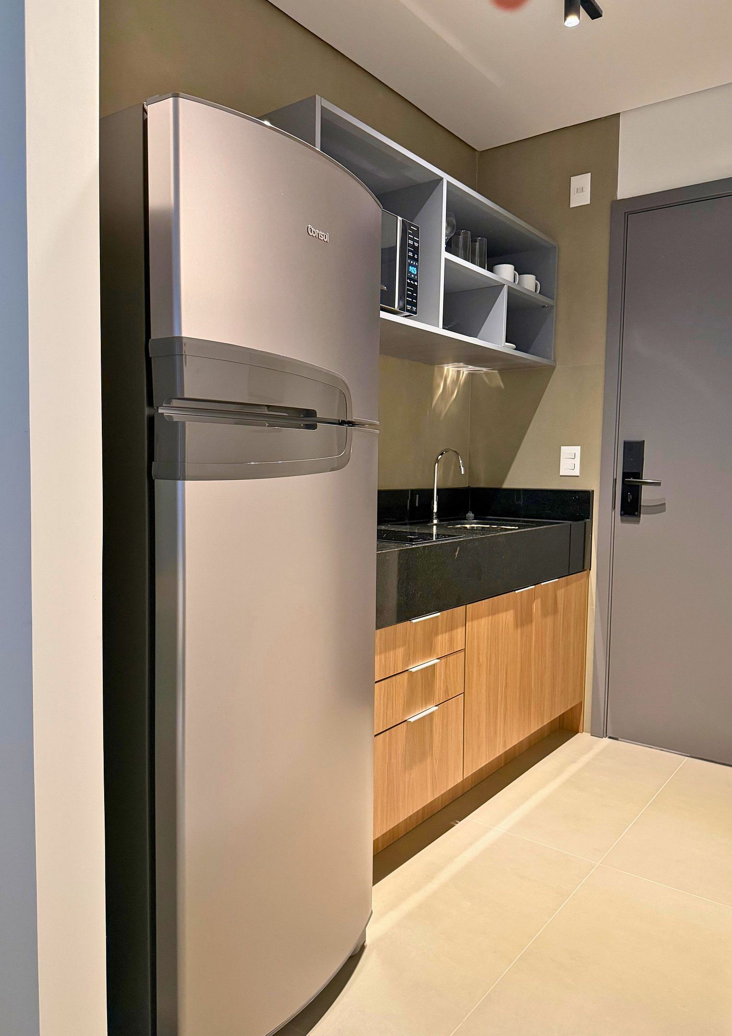 A modern kitchen with a built-in refrigerator, wooden cabinets, and a black countertop.