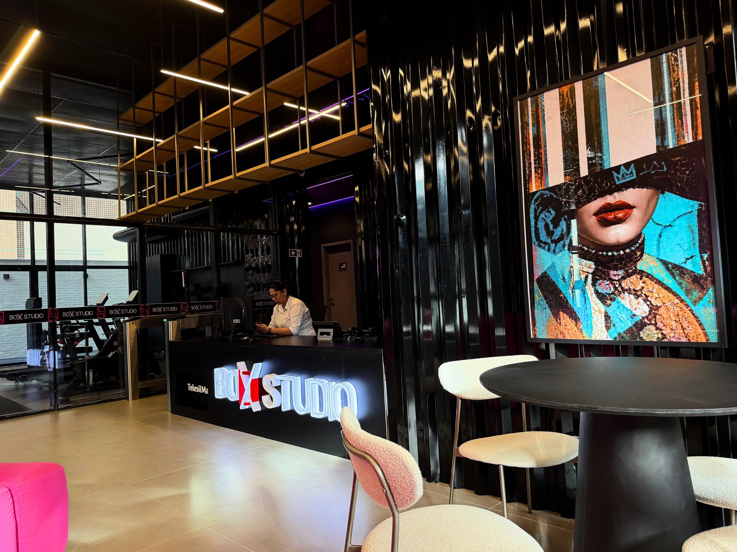 A modern interior with a reception desk, a large digital screen, and a bar area.