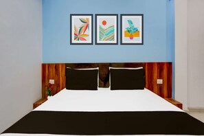 A room with a bed, a headboard with a wooden panel, and three framed artworks on the wall.