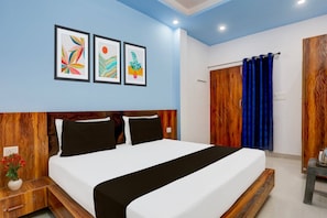 A bedroom with a bed, a nightstand, a wall with framed artwork, a wooden wardrobe, and a blue curtain.