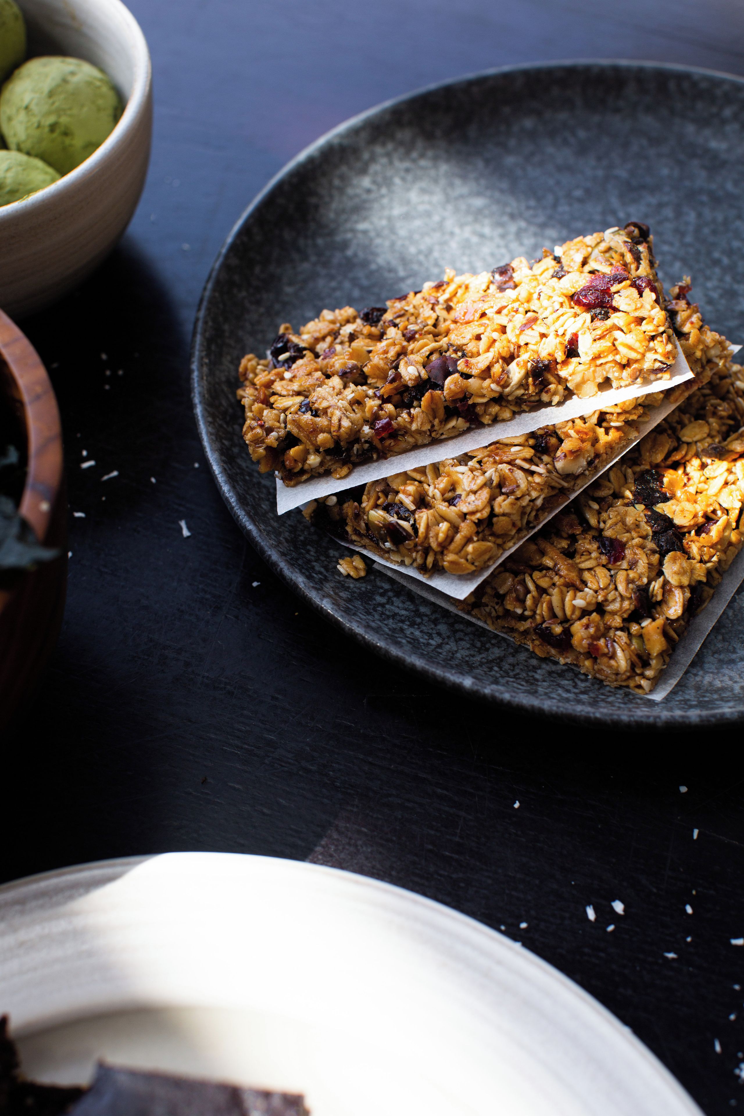 A plate with granola bars and a bowl of green fruit.