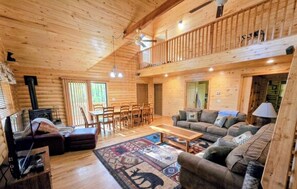 L’intérieur d’un chalet accueillant comprend un coin repas, un salon avec un canapé et une table basse, ainsi qu’un balcon doté d’une balustrade.