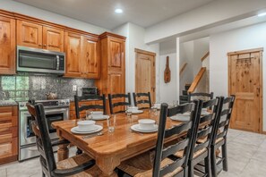 A kitchen with wooden cabinets, a microwave, a stove, and a dining table set for six. - Walk to Ski, Snowbird 204 Mountain Condo 684 (Mammoth Lakes)