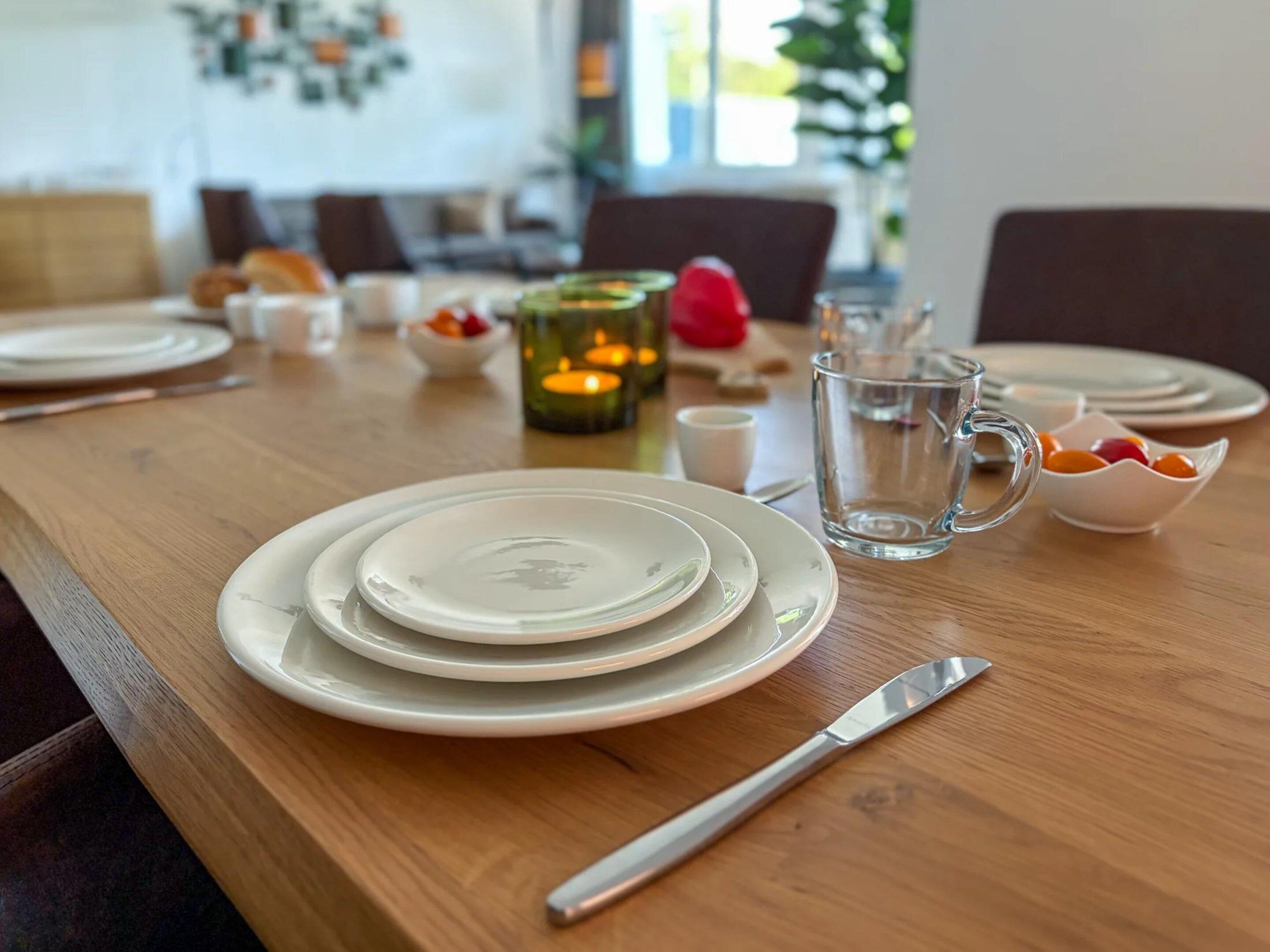 A dining table set with plates, a knife, a glass pitcher, and a candle.
