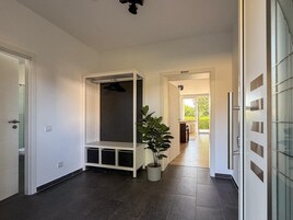 A hallway with a built-in bench, a potted plant, and a sliding glass door leading to a balcony.