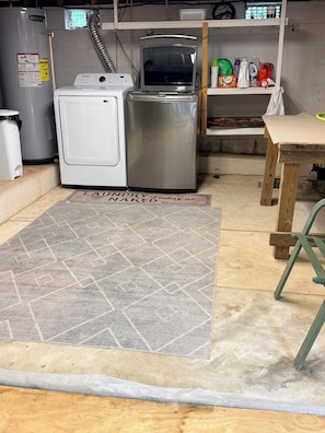 Un'area lavanderia con lavatrice, asciugatrice e scaldabagno in metallo.