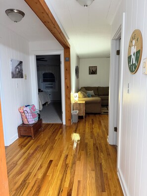 Una habitación con piso de madera, un sofá, una lámpara y un reloj de pared.