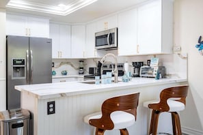 A modern kitchen with white cabinetry, stainless steel appliances, and a marble backsplash.