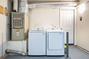 A laundry room with two white washers and dryers, a utility meter, and a door.
