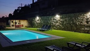 Una piscina con una parete in pietra e una zona patio con sedie.