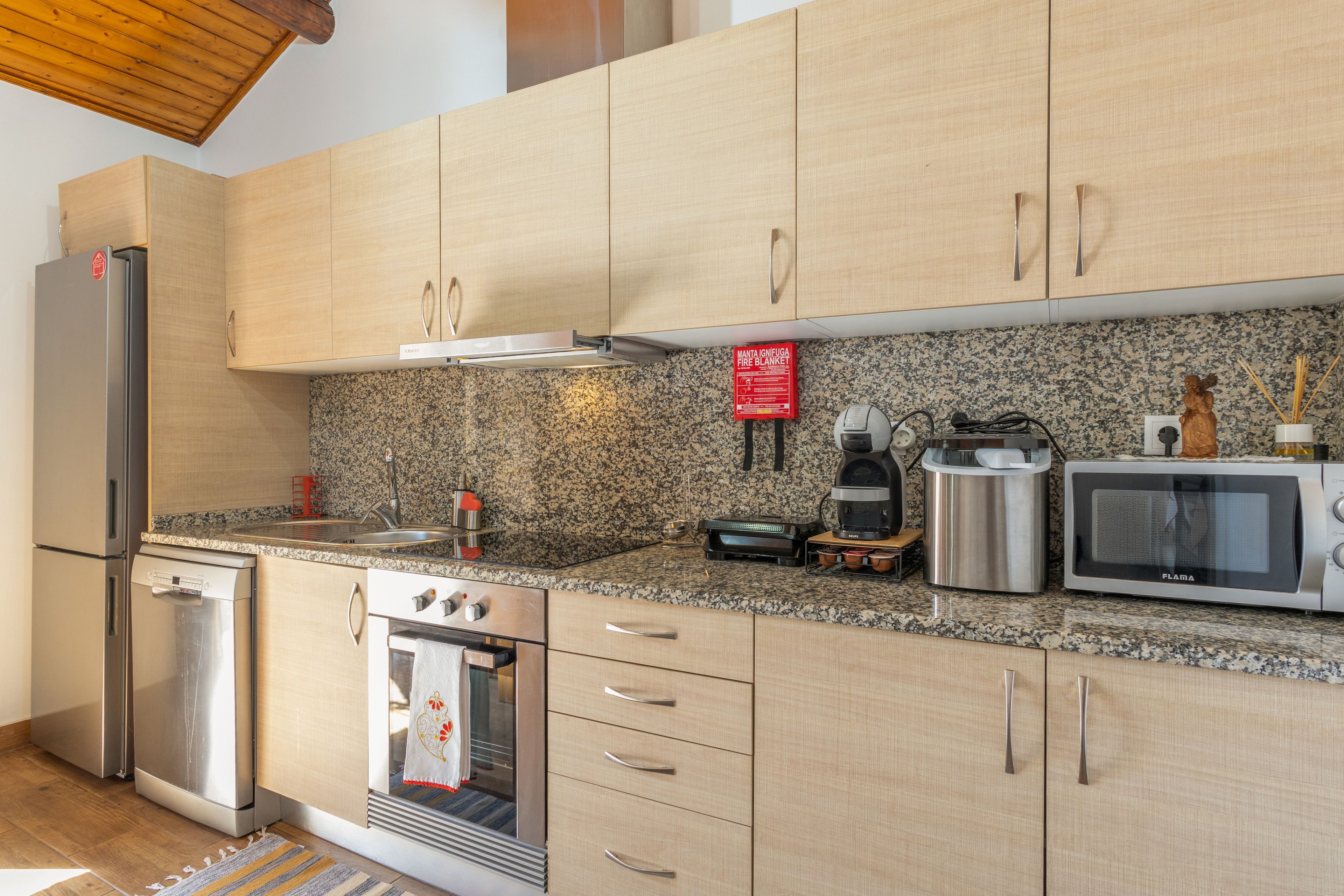 Una cocina moderna con electrodomésticos de acero inoxidable, encimeras de granito y armarios de madera.