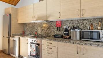 Una cocina moderna con electrodomésticos de acero inoxidable, encimeras de granito y armarios de madera.