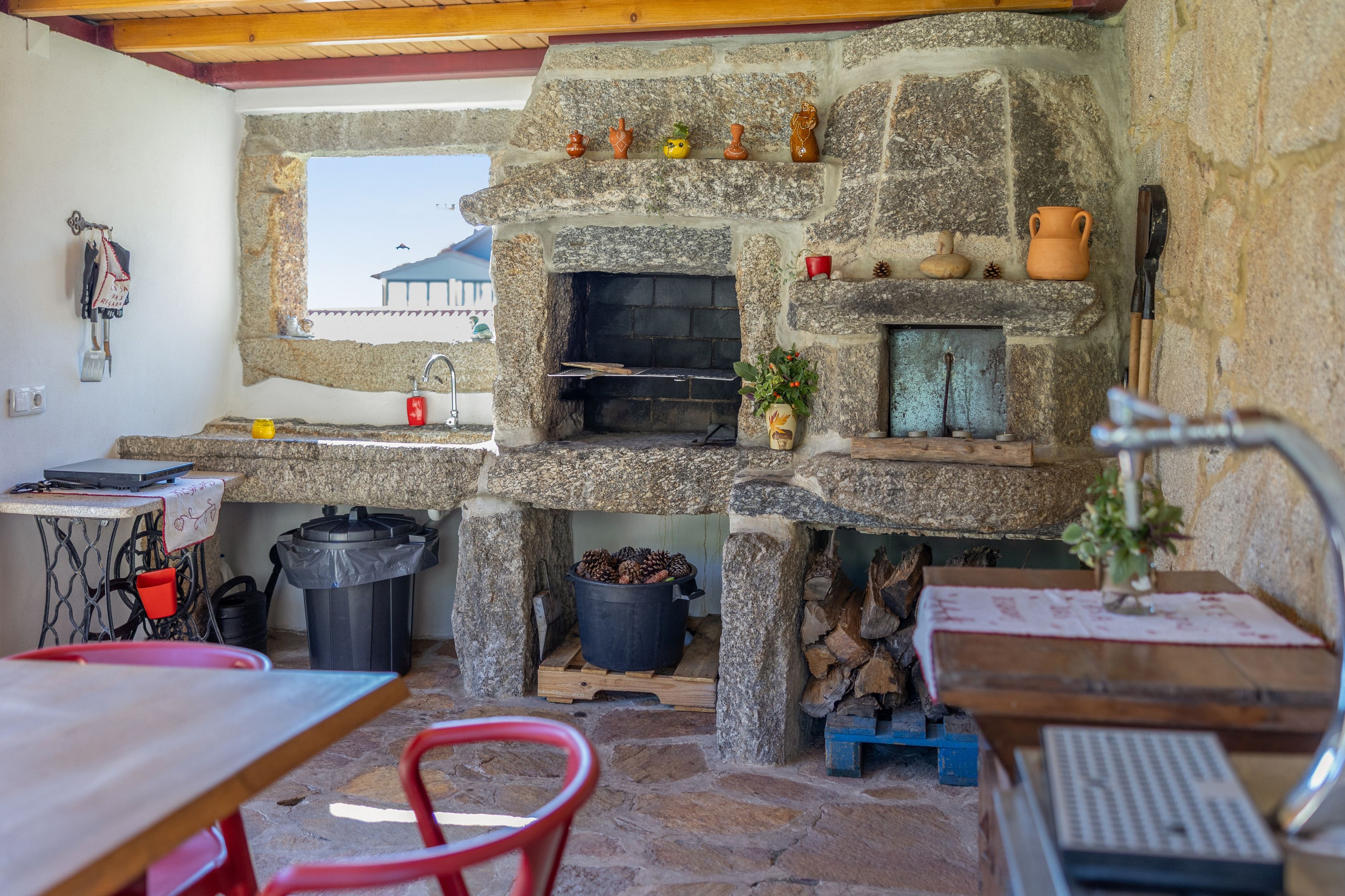 A stone-built kitchen with a built-in oven, a sink, and a window overlooking a mountainous landscape.