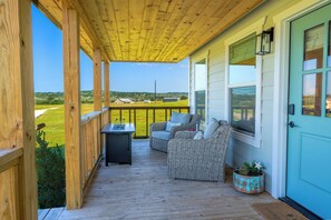 A wooden deck with outdoor furniture, a table, and a potted plant.