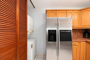 A kitchen with a stainless steel refrigerator, a built-in oven, wooden cabinets, and a tiled backsplash. - Ocean Views. Golden Evenings. Unforgettable Stays. (Rincón)