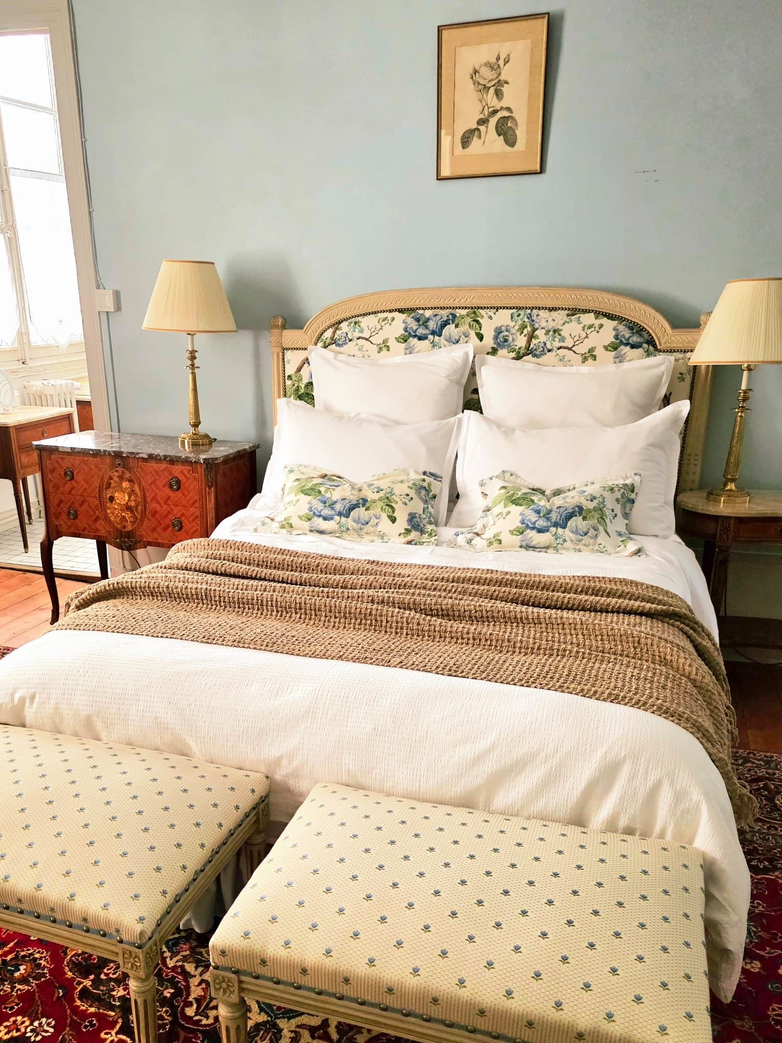 A bedroom with a bed, two bedside tables, a lamp, a chair, and a rug.