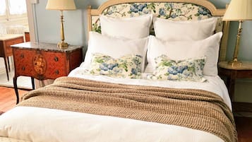 A bedroom with a bed, two bedside tables, a lamp, a chair, and a rug.