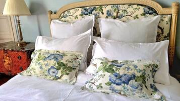 A bed with white bedding and floral-patterned pillows.