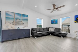 A modern living room with a sectional sofa, a blue cabinet, and artwork on the walls. - Oceanfront Marathon FL Home w/ Private Dock, Pool & Direct Ocean Access (Marathon)