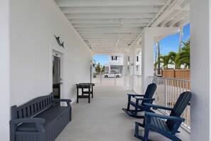 Ein überdachter Außenbereich mit einem Tischfußballtisch, Sitzgelegenheiten und Blick auf ein weißes Gebäude im Hintergrund.