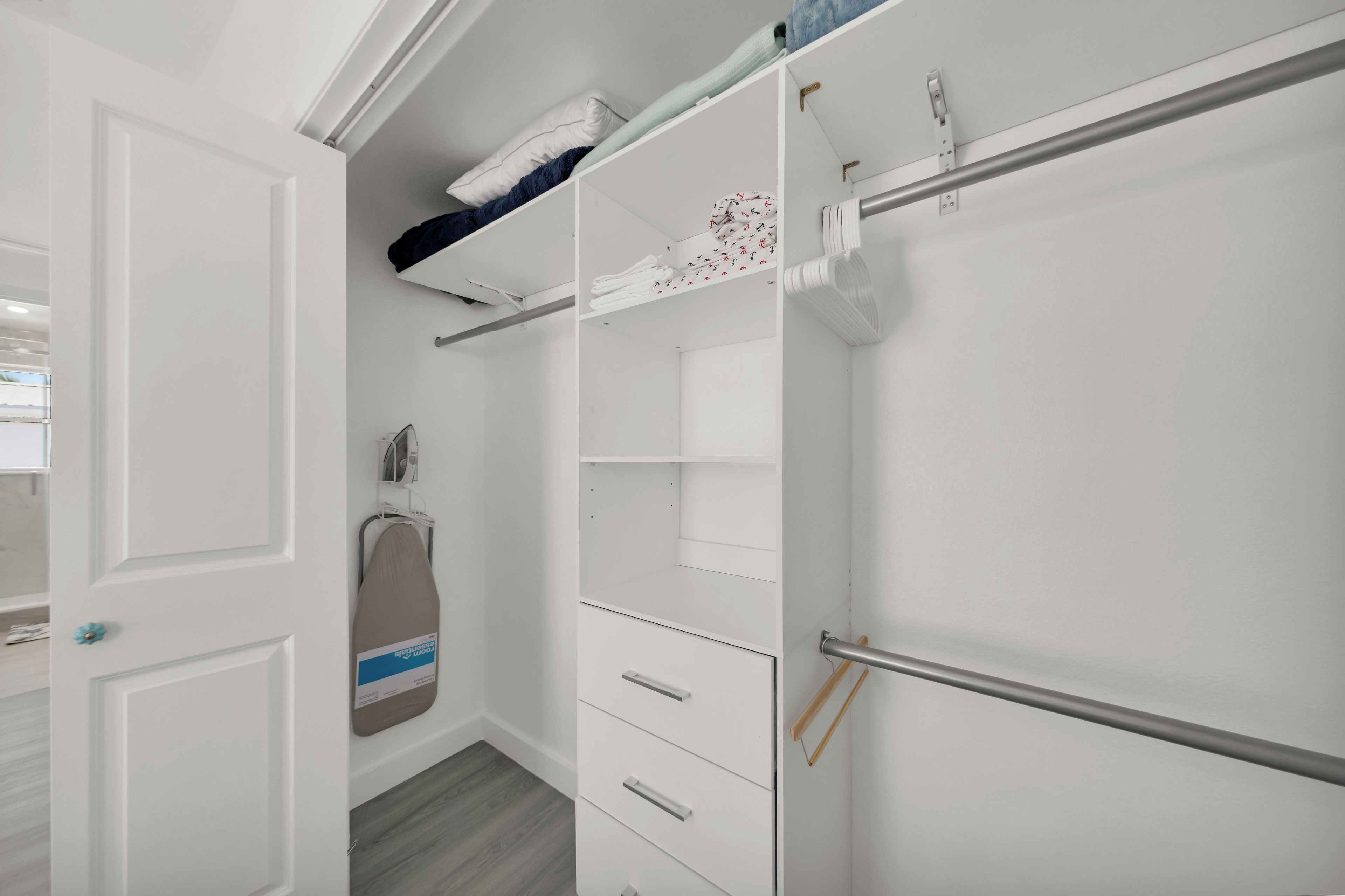 A walk-in closet with open doors, a hanging rack, and a storage unit.