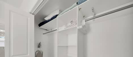 A walk-in closet with open doors, a hanging rack, and a storage unit.