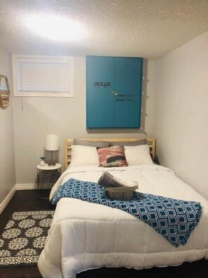 A bedroom with a bed, a blue wardrobe, a bedside table with a lamp, and a patterned rug. - Studio - Close to Woodstock Hospital (Woodstock)