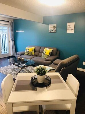 A living room with a sofa, coffee table, and a dining table with chairs. - Studio - Close to Woodstock Hospital (Woodstock)