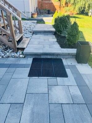 A paved pathway leading to a wooden deck with a metal grate in the center. - Studio - Close to Woodstock Hospital (Woodstock)