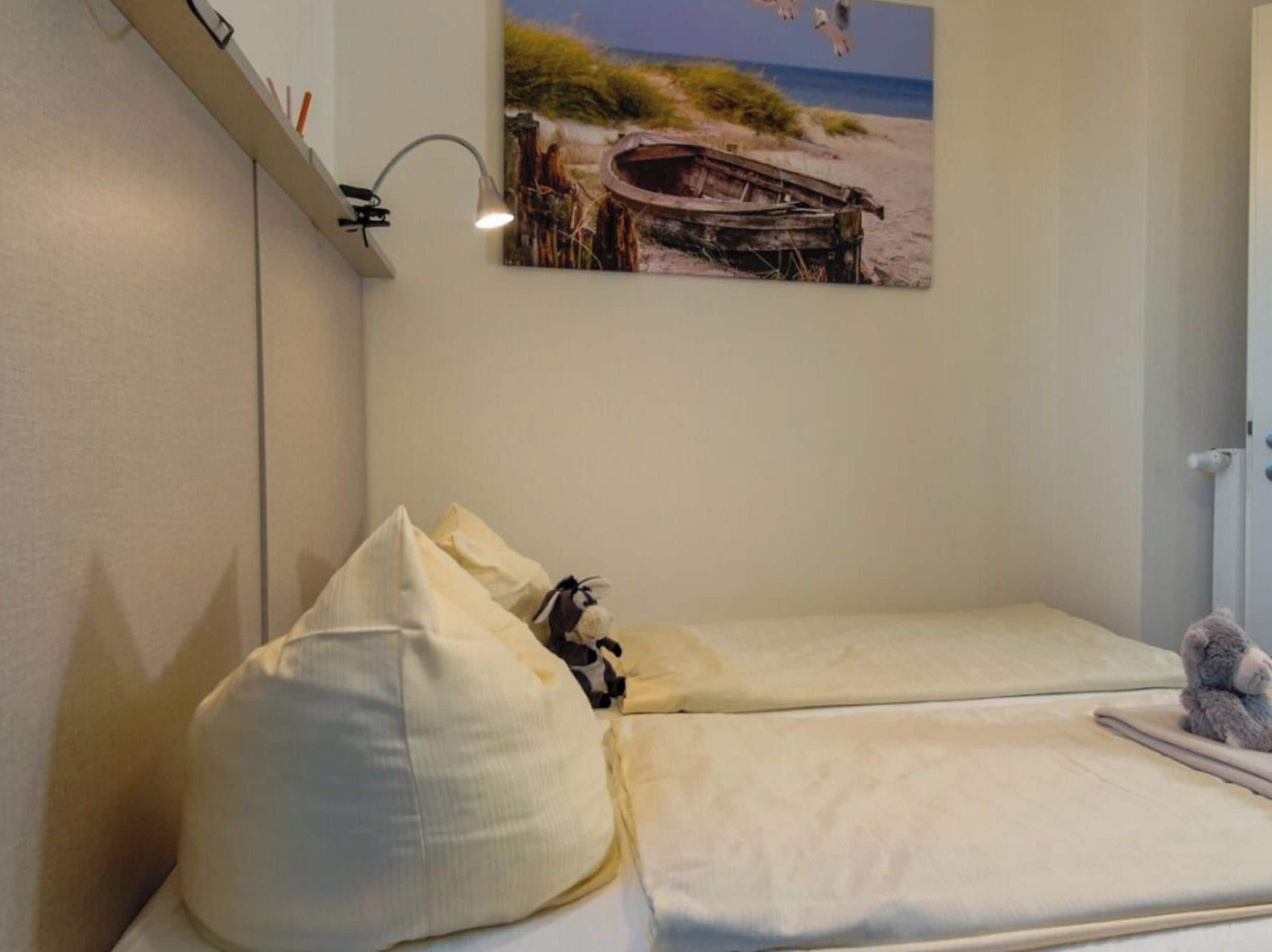 Quarto com cama, luminária na parede e quadro com paisagem de praia.