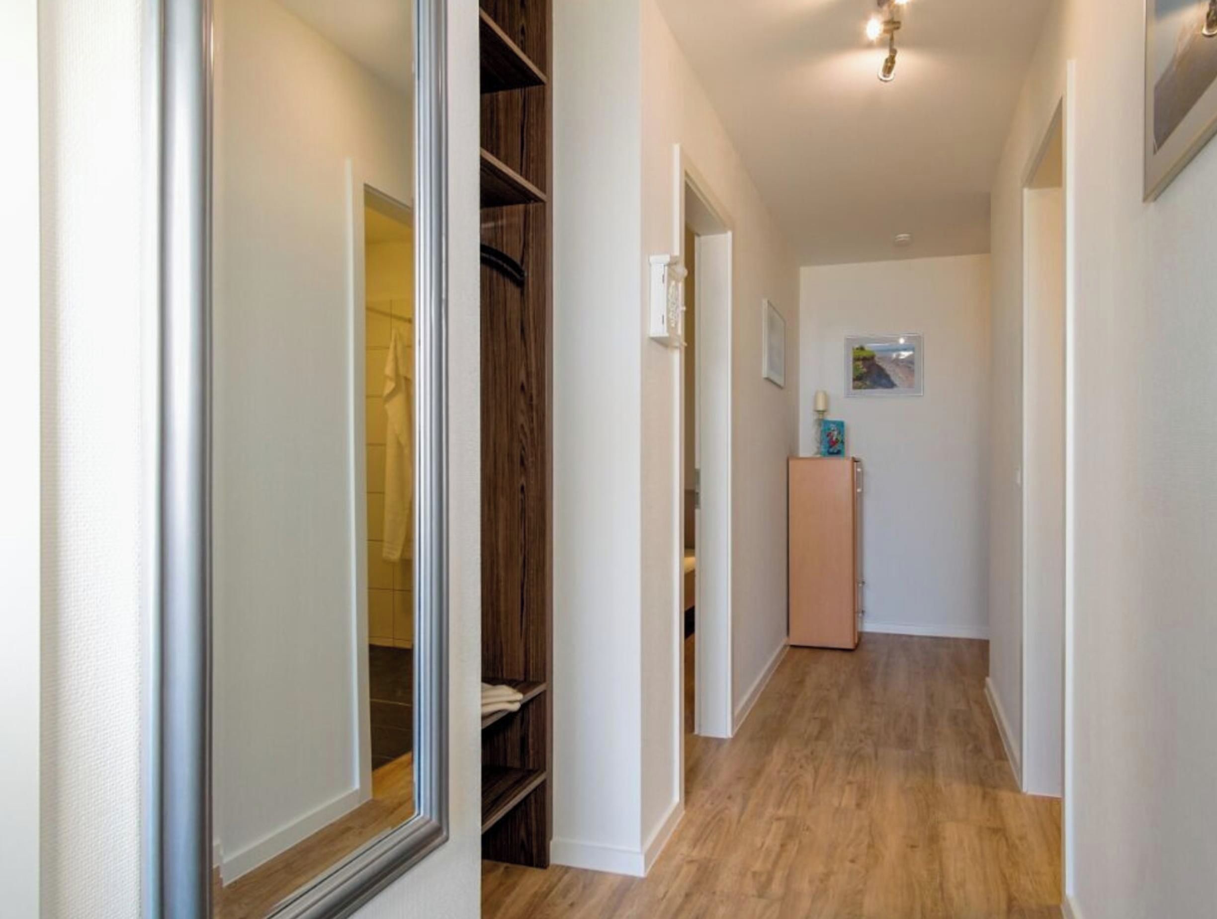 Un couloir avec un plancher en bois, une armoire et un petit meuble.