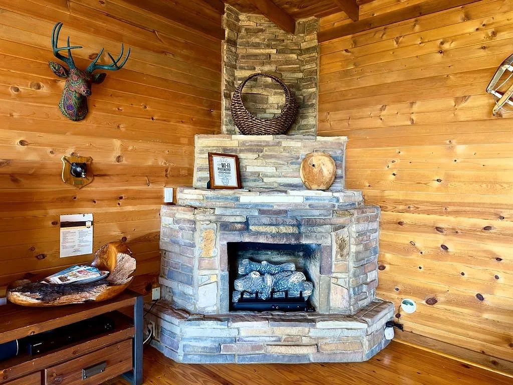 A stone fireplace with a basket on top, surrounded by wooden walls and a deer head decoration.
