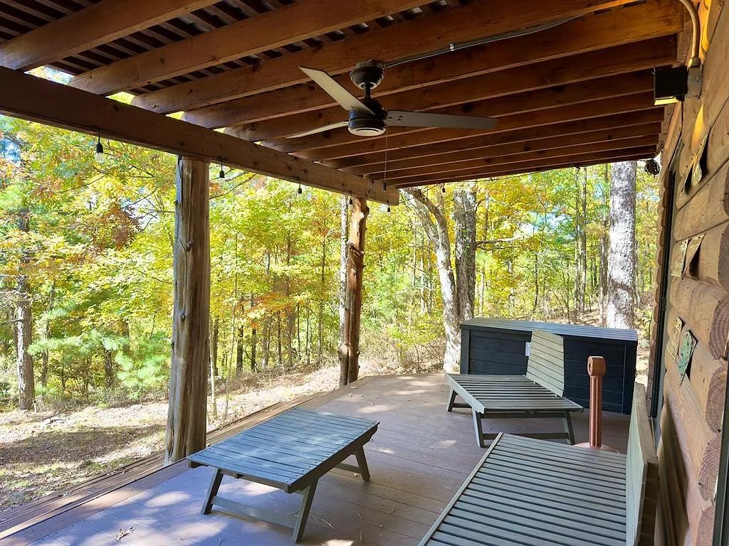 A covered outdoor deck with wooden benches and a ceiling fan.