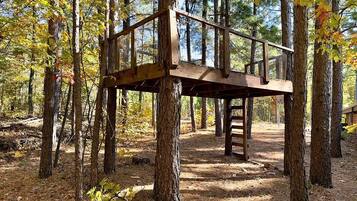 A rustic wooden platform structure in a forested area.