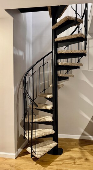 A spiral staircase with a black metal railing and carpeted steps. - Cozy 2 bedroom 2 bathroom with game room right in the Mountains of Vernon, NJ (Vernon Township)