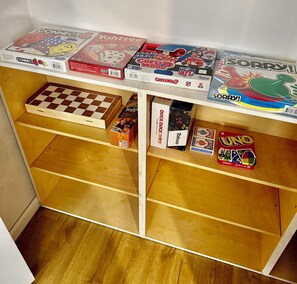 A wooden shelf with various board games and a checkered game board. - Cozy 2 bedroom 2 bathroom with game room right in the Mountains of Vernon, NJ (Vernon Township)